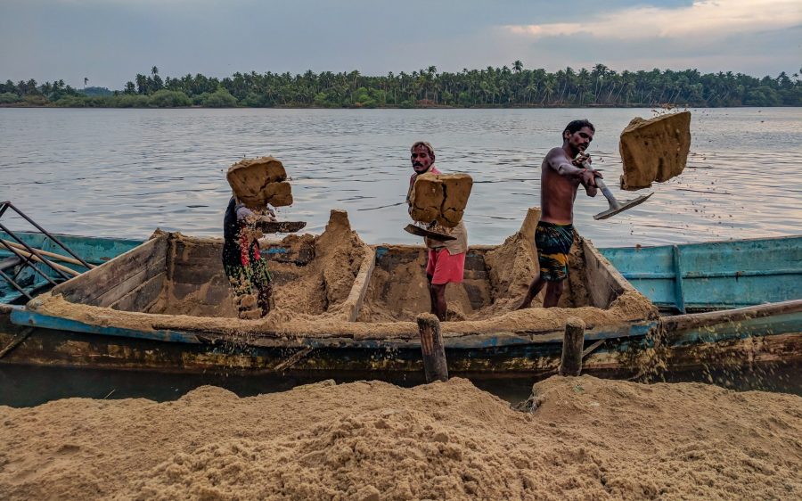 Guys shoveling sand from a boat