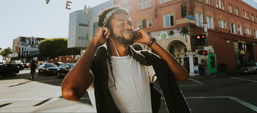 A guy on a street corner listening to earbuds.