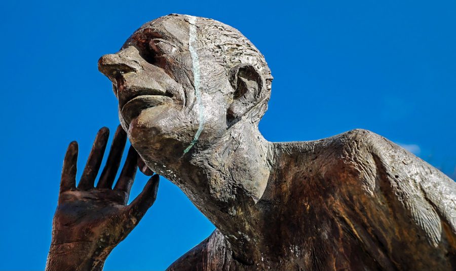 A creepy statue with its hand by its ear as if listening.