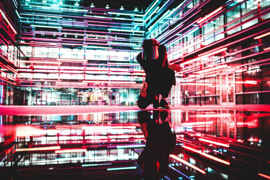 Photo of a person kneeling among neon light trails