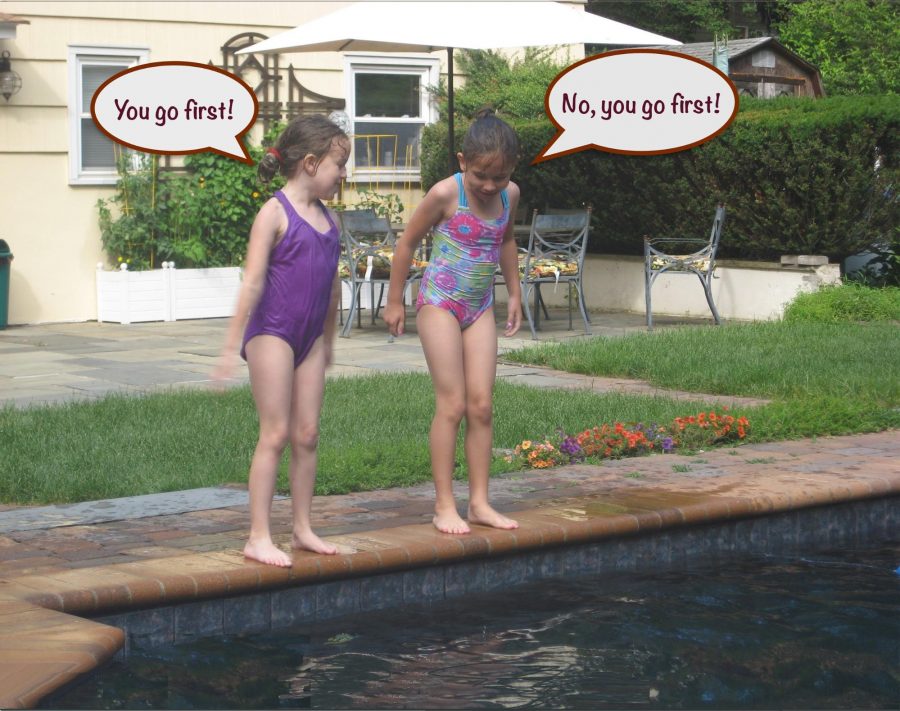 Two girls debating diving into a pool.
