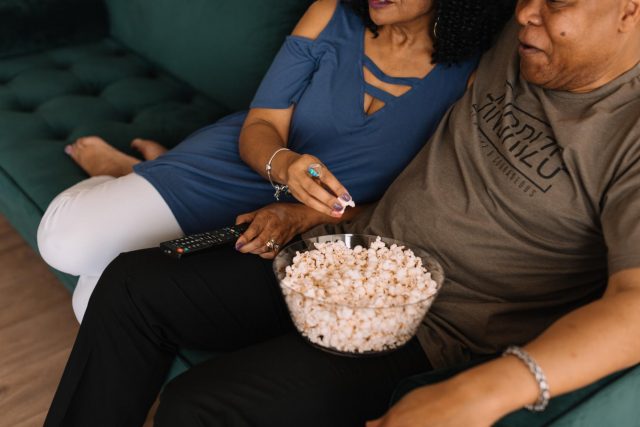 A couple eating popcorn on a couch