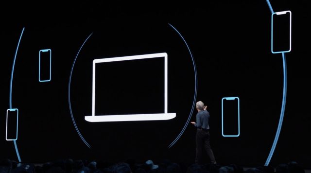 Craig Federighi in front of a screen showing an illustration of a Mac broadcasting Bluetooth keys to iOS devices.